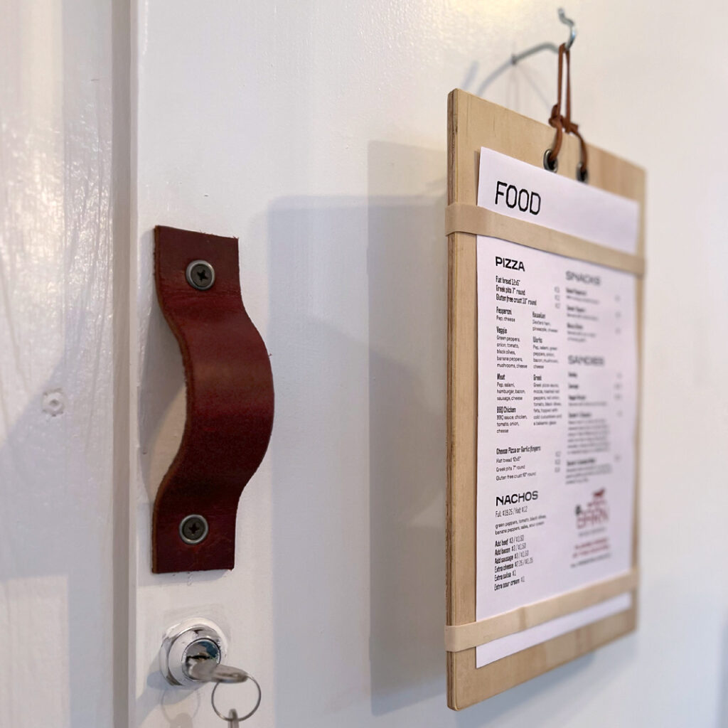 Menu hanging ontop of a wooden board on a white door with leather handle